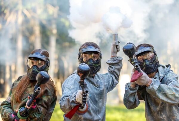 Grupa osób w maskach ochronnych grająca w paintball dla firm.