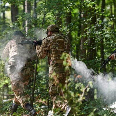 Trzech mężczyzn w lesie bierze udział w grze Paintball dla firm.