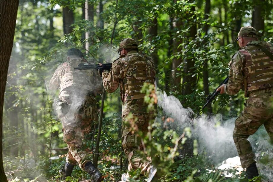 Trzech mężczyzn w lesie bierze udział w grze Paintball dla firm.