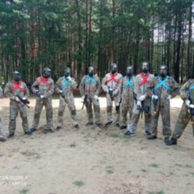 Grupa mężczyzn biorąca udział w Paintball na wieczór kawalerski w lesie.