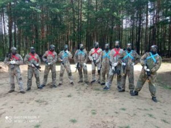 Grupa mężczyzn biorąca udział w Paintball na wieczór kawalerski w lesie.