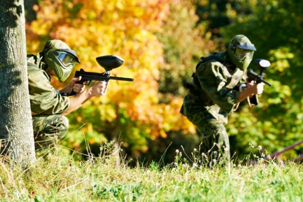 Dwóch mężczyzn ubranych w stroje do paintballa gra na świeżym powietrzu w kolorowych jesiennych liściach – Paintball dla grup zorganizowanych.