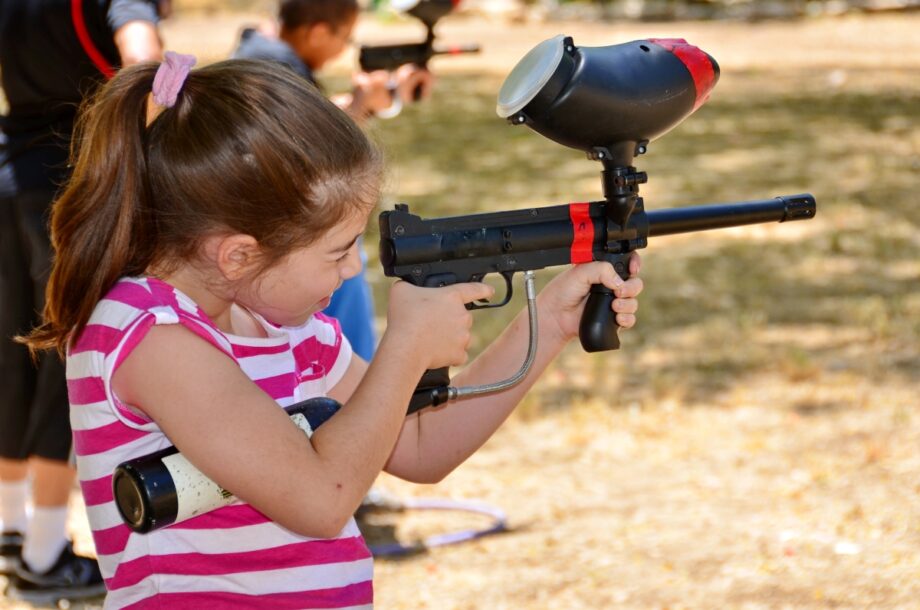 Dziewczynka cieszy się grą podczas paintballowych urodzin dla dziecka.