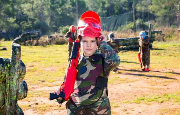 Dziecko w stroju paintballowym świętuje swoje urodziny na paintballu.